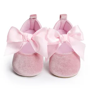 Detail van roze fluwelen baby prinsessenschoenen met grote decoratieve satijnen strikken