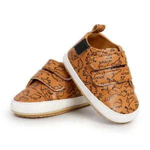 Detailed view of brown baby walking shoes with black dinosaur patterns and velcro straps.