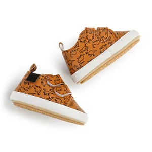 Stylish brown baby walking shoes featuring cute dinosaur patterns and hook-and-loop straps