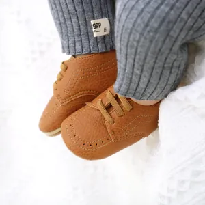 Close-up of brown PU leather baby shoes with brogue detailing and soft laces