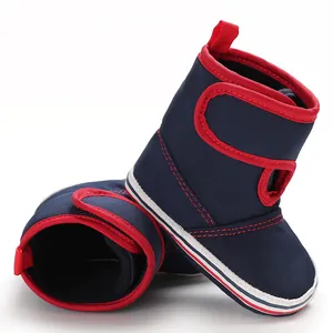 Macro detail of navy blue canvas baby walking boots featuring red trim and soft striped soles