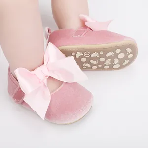 Close-up van roze fluwelen babyschoentjes met een grote strik en een antislipzool