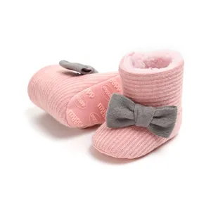 Detail view of pink knitted baby snow boots with grey bow and warm fleece lining