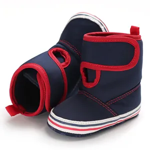 Close-up view of navy blue baby soft sole walking boots with red trim and velcro closure