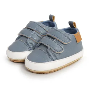 Close-up detail of blue baby sneakers featuring double hook-and-loop straps and textured upper