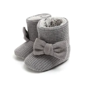 Close-up detail of grey knitted baby snow boots featuring plush lining and soft bow