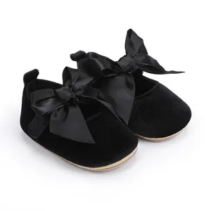 Detailweergave van zwarte baby-prinsessenschoenen met grote satijnen strikken en corduroy