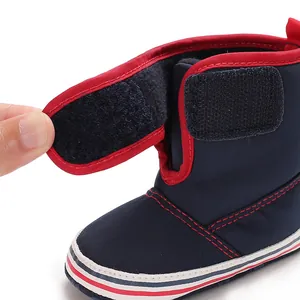 Detail view of soft-soled navy baby walking boot with adjustable red velcro strap