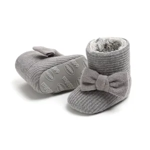 Close-up of grey knit baby snow boots featuring a cute bow and warm plush lining inside.