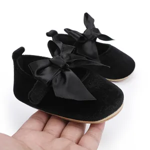 Detailopname van zwarte fluwelen baby prinsessenschoenen met een elegante satijnen strik