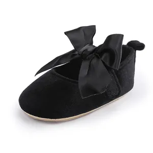 Close-up van zwarte fluwelen baby prinsessenschoenen met een grote satijnen strik.