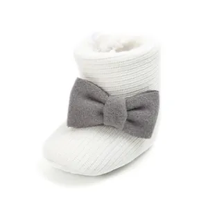 Macro shot of the soft knitted texture and grey decorative bow on a white baby bootie