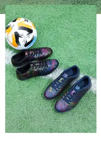Gros plan de chaussures de football noires aux motifs craquelés colorés sur gazon
