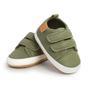 Detail of olive green baby walking shoes with hook-and-loop straps and white soles