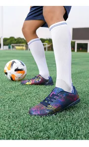 Détail de chaussures de football colorées avec motif éclair sur gazon artificiel