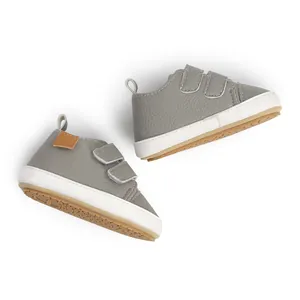 Detail view of grey toddler walking shoes with velcro straps and white rubber soles for safety