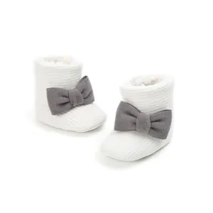 Close-up detail of white knit baby winter boots with soft fleece lining and grey bow