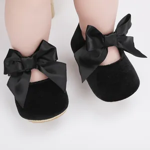 Detailopname van zwarte fluwelen baby prinsessenschoenen met grote satijnen strikken