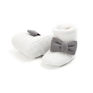 Detail view of white baby knit snow boots featuring a soft grey bow and warm plush lining
