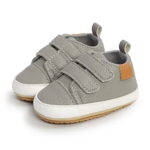 Detailed view of grey baby walking shoes featuring double velcro straps and soft white rubber sole
