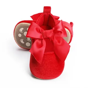 Detailopname rode fluwelen baby prinsessenschoenen met grote satijnen strik en antislipzool.