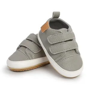 Close-up detail of grey textured faux leather baby walker shoes with white rubber soles