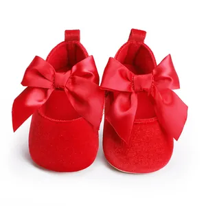 Detailweergave van rode fluwelen babyprinsessenschoenen met een grote satijnen strik.