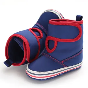 Detailed view of dark blue baby boots with soft soles and red trim for walking