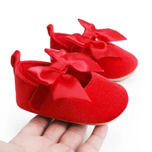 Detailopname van rode fluwelen baby prinsessenschoentjes met grote satijnen strik
