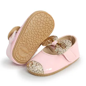 Detailed view of pink baby girl princess shoes with gold glitter bow and soft rubber sole