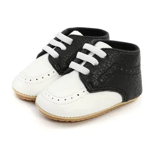Close-up of black and white leather baby walking shoes with brogue details.
