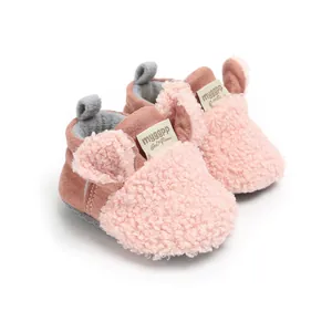Close-up of pink fuzzy baby winter shoes with cute ear decorations and soft sole.