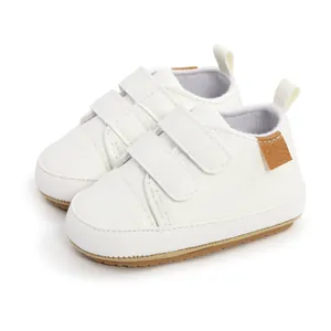 Close-up detail of white infant walking shoes featuring soft soles and velcro straps