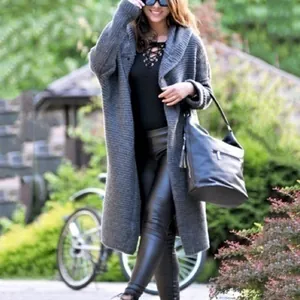 Women's long grey knit cardigan sweater styled with black leather leggings in a garden.