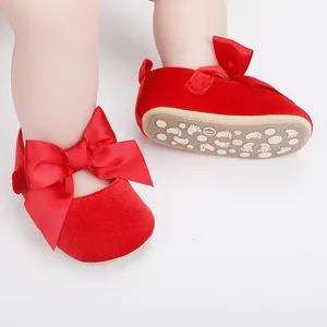 Detail van rood fluwelen babyschoentjes met grote satijnen strik en antislipzool
