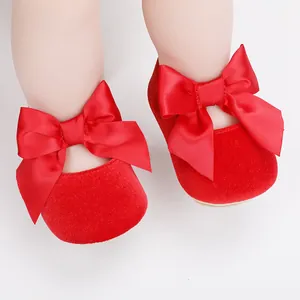 Detailopname van elegante rode fluwelen babyschoentjes met een decoratieve satijnen strik