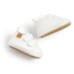 Macro view of white baby walking shoes featuring soft pebble grain leather and velcro straps