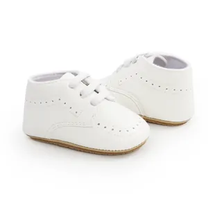 Close-up of white PU leather baby walker shoes with soft soles and brogue details