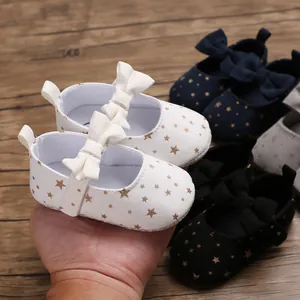 Nahaufnahme weißer Baby-Prinzessinenschuhe mit Goldsternen und niedlicher Schleife