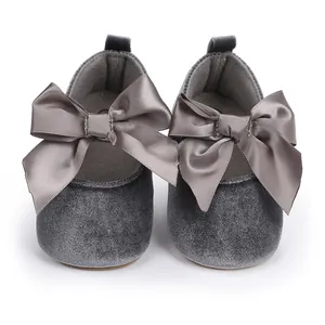 Close-up van grijze fluwelen babyschoentjes met grote decoratieve satijnen strikdetails
