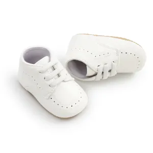 Close-up detail of white soft-soled baby walking shoes with elegant brogue perforations