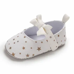 Makro-Detail von weißen Baby-Lernlaufschuhen mit goldenem Sternmuster und Schleife