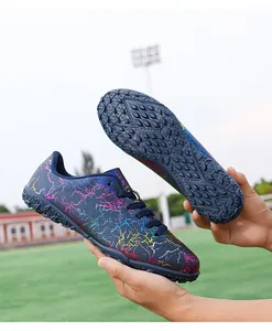 Vue rapprochée détaillée de chaussures de foot avec motif craquelé coloré et semelle turf