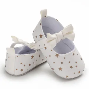 Nahaufnahme weißer Baby-Prinzessinenschuhe mit goldfarbenem Sternmuster und Schleife
