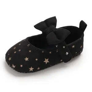 Detailansicht schwarzer Baby-Prinzessinenschuhe mit funkelnden goldenen Sternen und Schleife.