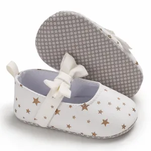 Nahaufnahme von Baby-Prinzessinenschuhen mit goldenen Sternen, Schleife und rutschfester Sohle.