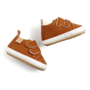 Side view detail of brown baby walking shoes with dual velcro straps and white sole