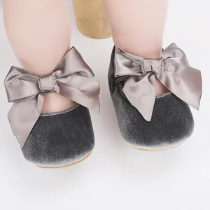 Close-up van babymeisje grijze fluwelen prinsessenschoenen met grote satijnen strikken