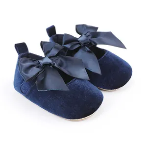 Detailopname van marineblauwe fluwelen baby prinsessenschoenen met satijnen strikken