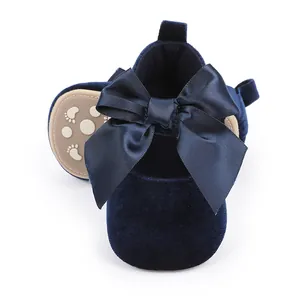 Detail van marineblauwe fluwelen babyschoentjes met een grote en elegante satijnen strik erop